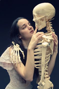 a woman holding a skeleton in her hands