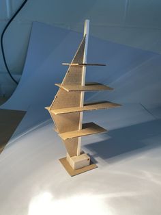 a model of a sailboat made out of cardboard sitting on a white table top