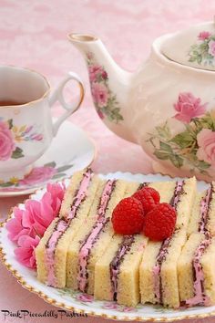 a piece of cake on a plate with raspberries next to a teapot