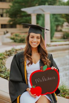 a woman in a graduation gown holding an apple and blackboard with the word ms pocinoo written on it