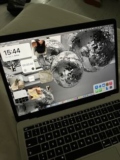 an open laptop computer sitting on top of a white table covered in shiny disco balls