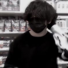 a person wearing a black mask and gloves in front of shelves with hair dryers