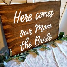 a wooden sign that says here comes our mom the bride