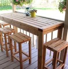 a wooden table sitting on top of a wooden floor next to two stools and a potted plant