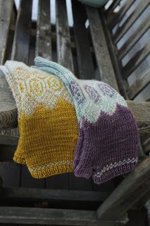 two knitted mitts sitting on top of a wooden bench next to a bowl