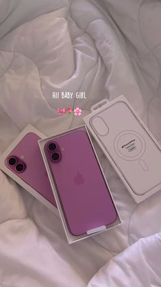 two iphones are laying on a bed with white sheets and pink cases in them