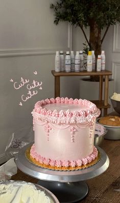 a pink cake sitting on top of a wooden table next to other cakes and pies