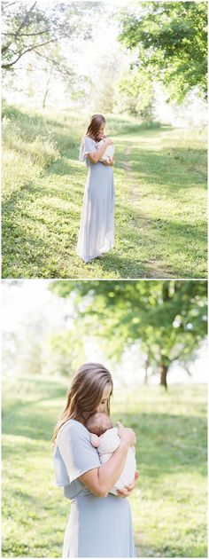 a woman holding a baby in her arms while standing on the grass with trees behind her