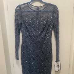 a blue dress with sequins on it hanging from a hanger in front of a door