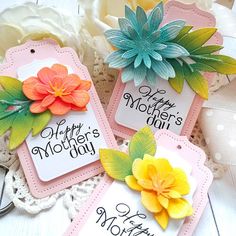 three tags with flowers on them sitting next to each other