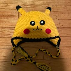 a crocheted hat with ears and eyes on top of a wooden floor next to a string