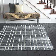 a white and black area rug in front of a stair case next to a bench