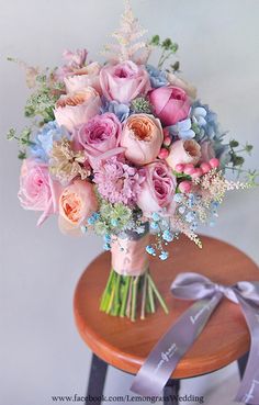 a bouquet of flowers sitting on top of a wooden table next to a purple ribbon