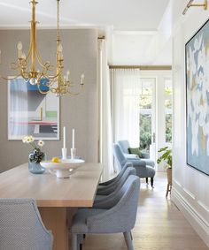 a dining room table with blue chairs and a chandelier hanging from the ceiling