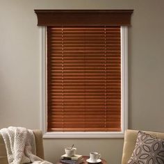 a living room with two chairs and a coffee table in front of a window that has blinds on it