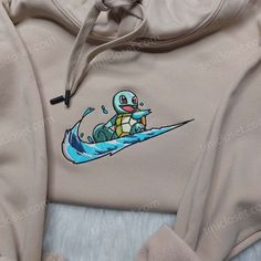 the hoodie has an image of a turtle riding a wave on it's back