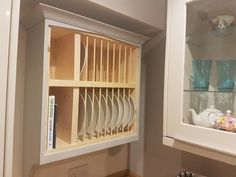 a kitchen cabinet with plates and cups in it