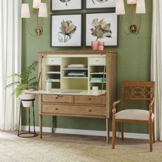 a living room with green walls and pictures on the wall, two chairs and a desk