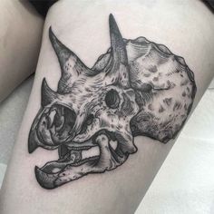 a black and white rhino skull tattoo on the thigh