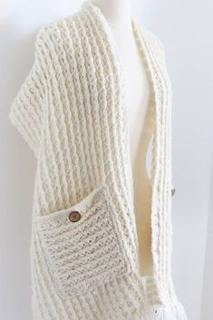 a mannequin wearing a white knitted cardigan with two pockets and buttons