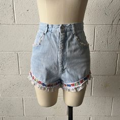 These 1990's vintage Extra Femme shorts are made from a light washed, cotton denim and white, nylon lace. Features a high waisted fit with floral ribbon around either leg and white, ruffled lace trim. Zips in front to a single button closure at the waist. A couple small tears in the lace that aren't noticeable but reflected in price. In overall excellent vintage condition with only minimal signs of wash and wear.   Marked a size 7, see below for measurements 25" waist 36" hips 13" rise 3" inseam Retro Bottoms With Frayed Hem For Spring, High Waist Cotton Bottoms With Lace Trim, High-waist Cotton Bottoms With Lace Trim, Retro Light Wash Jeans For Summer, Retro Cotton Shorts With Frayed Hem, Retro Spring Jeans With Frayed Hem, Retro Jeans With Frayed Hem For Spring, Vintage Jeans With Frayed Hem For Spring, Fitted Denim Bottoms With Lace Trim