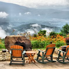 three lawn chairs sitting on top of a patio next to a fire pit with mountains in the background