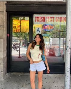 a woman standing in front of a store with her hands on her hips and looking at the camera