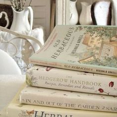 a stack of books sitting on top of a table next to vases and dishes