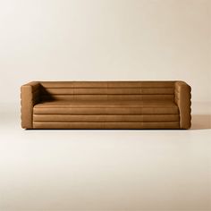 a brown leather couch sitting on top of a white floor next to a beige wall