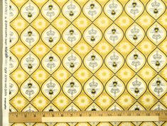 a yellow and white wallpaper with bees in the center, on top of a ruler