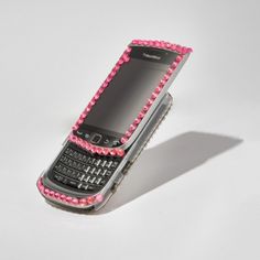 a cell phone with pink beads on the front and back cover, sitting upright against a white background