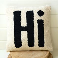 a black and white pillow with the letter h on it sitting on a wooden stool