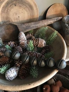 some pine cones and spoons are in a bowl on a table with other items