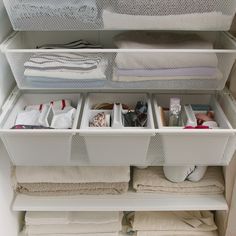 an organized closet with folded towels and other items in it, including clothes on the bottom shelf