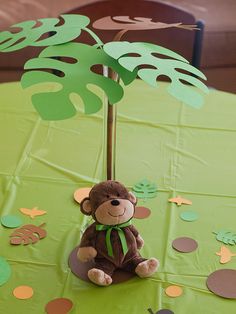 a stuffed monkey sitting on top of a table next to a green cloth covered tablecloth