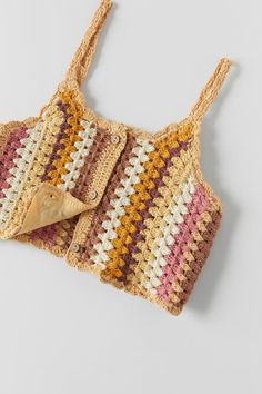 a crocheted bag is laying on the floor with a wooden spoon in it