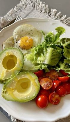 an egg, avocado, tomatoes and lettuce on a plate