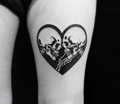 a woman's thigh with two skulls in the shape of a heart on it