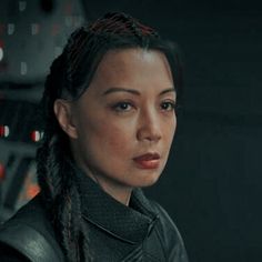 a woman with braids on her hair in a black leather jacket looking at the camera