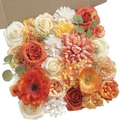 an arrangement of orange and white flowers in a cardboard box