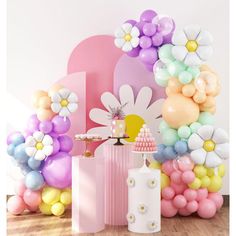 an assortment of balloons and decorations in front of a pink wall with flowers on it