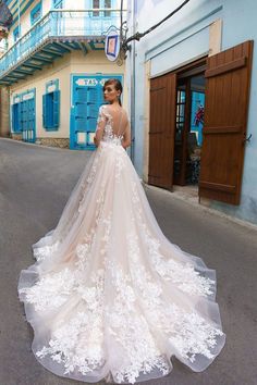 a woman in a wedding dress is standing on the street with her back to the camera