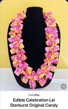 a pink and yellow necklace on a black mannequin headdress with bows