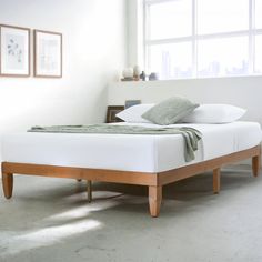 a bed sitting in the middle of a room next to two framed pictures on the wall