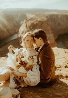 a bride and groom sitting on top of a cliff