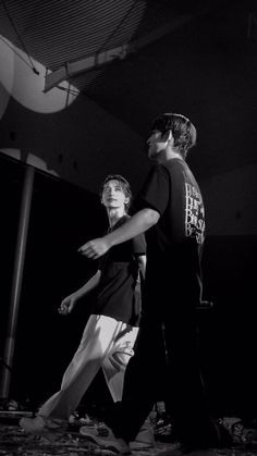 two young men are walking together in the dark