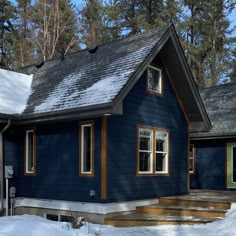 a blue house with snow on the ground and steps leading up to it's front door