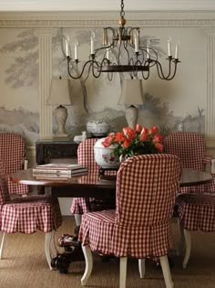 a dining room with red and white checkered chairs around a wooden table in front of a chandelier