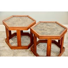 two wooden tables sitting on top of a floor next to each other in front of a wall