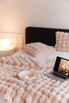 a laptop computer sitting on top of a bed next to pillows and a light bulb